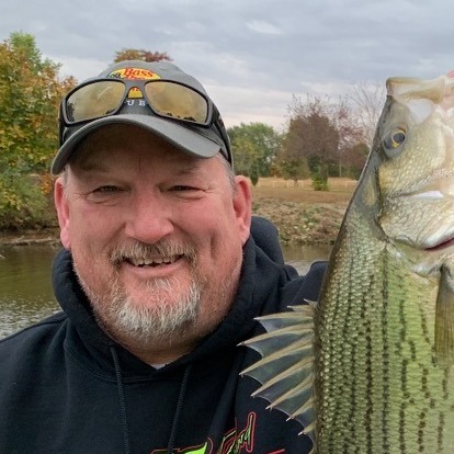 Richard holding a fish by the water